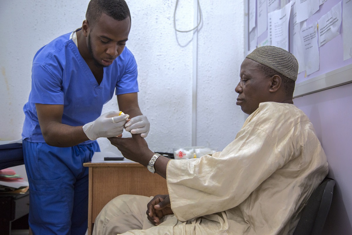 IMAGE OF DOCTOR CHECKING A PATIENT'S BLOOD SUGAR LEVEL